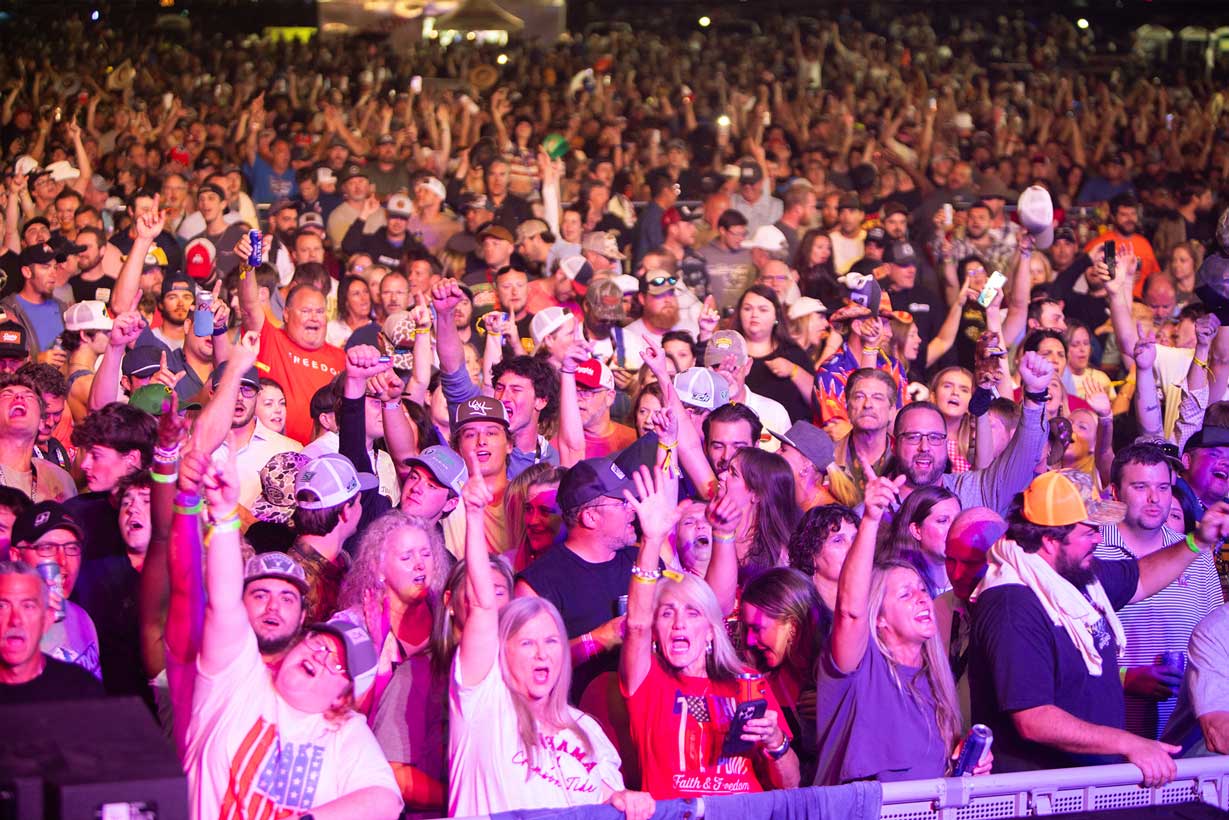 Large crowd of fans cheering during a nighttime concert at Talladega Superspeedway