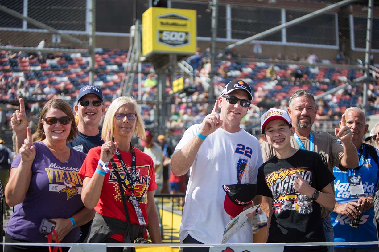 Group of NASCAR fans posing together and holding up number one signs at Talladega Superspeedway.