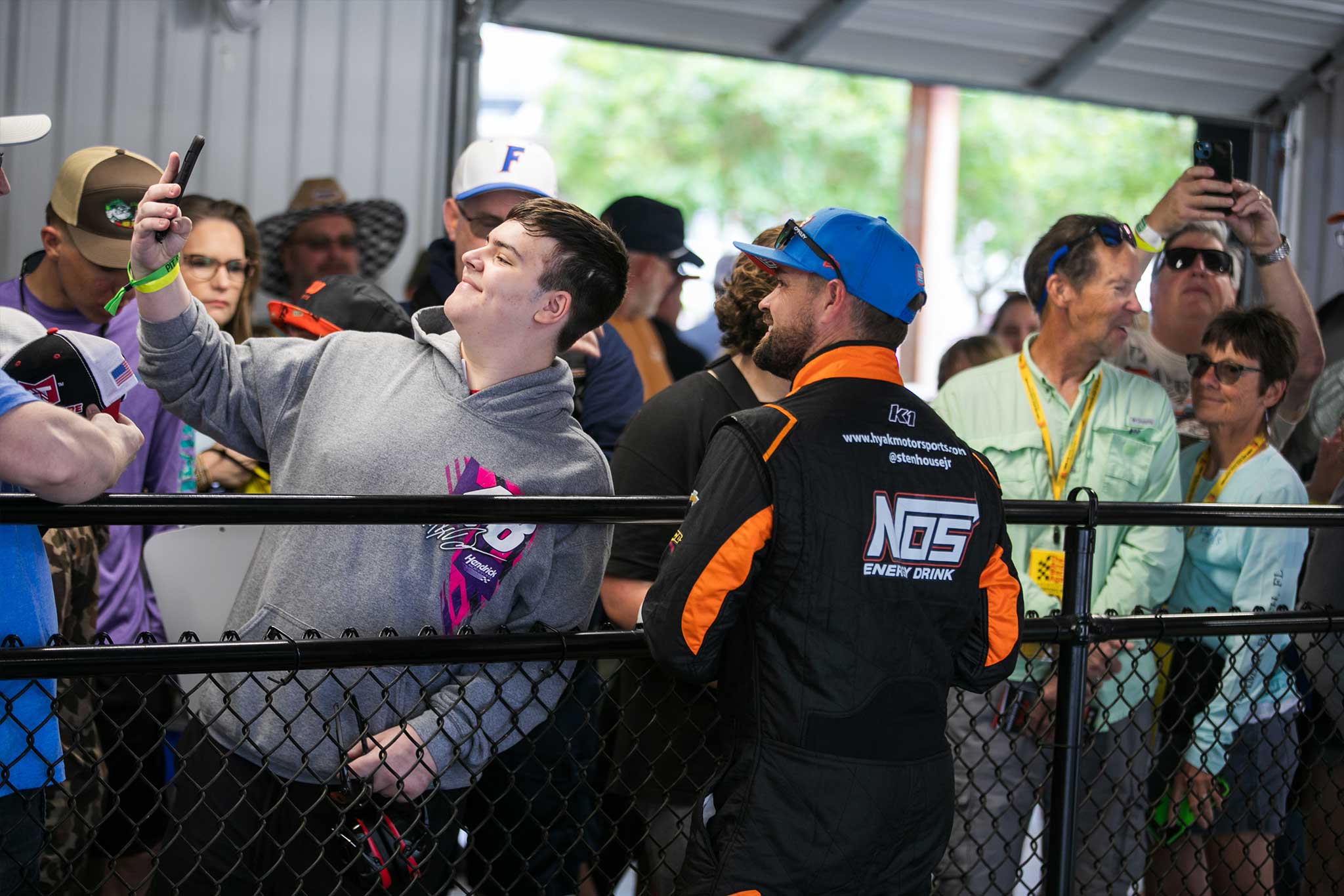 NASCAR fan taking a selfie with a driver inside the Talladega Garage Experience at Talladega Superspeedway
